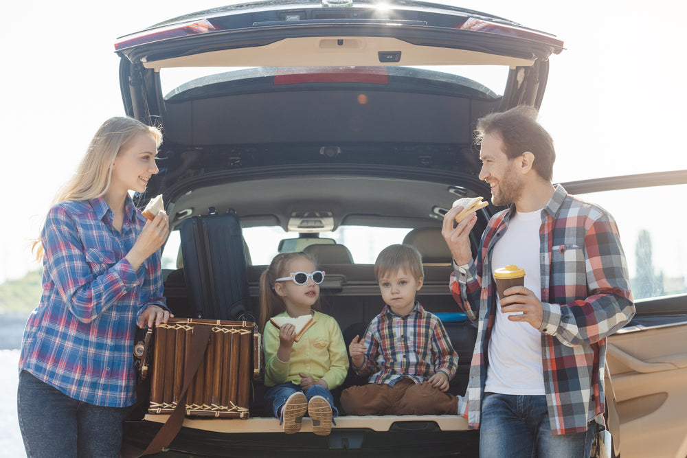 A family indulges in their healthy roadtrip snacks during a break from driving.