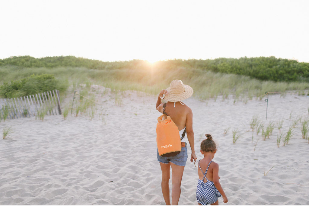 Picture of a Mom and daughter walking off the beach at sunset. Mom is carrying an IceMule Classic on her back.