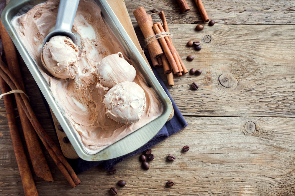 Homemade ice cream sits in a pan on a wooden background.